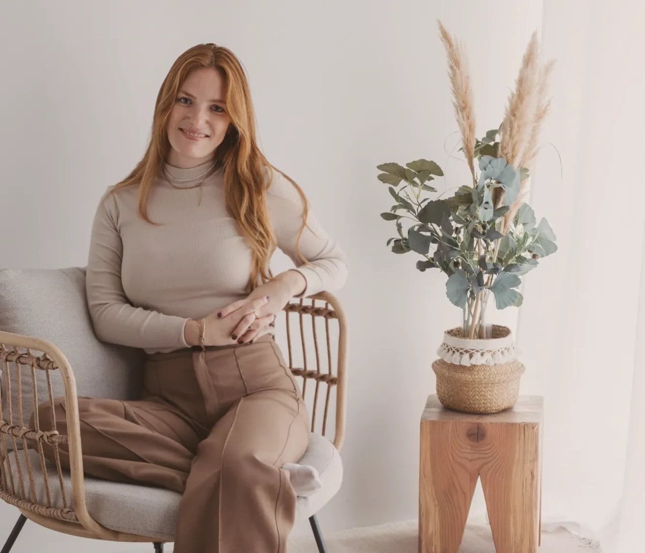 Nadine Stievermann sitzt in einem Rattansessel neben einem Beistelltisch.